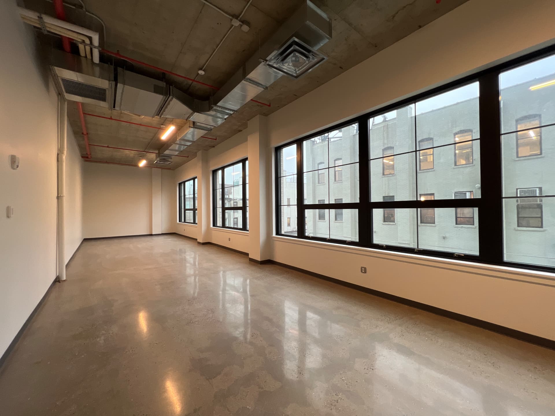 Loft floor with a run of oversized black steel windows overlooking neighboring Gowanus buildings